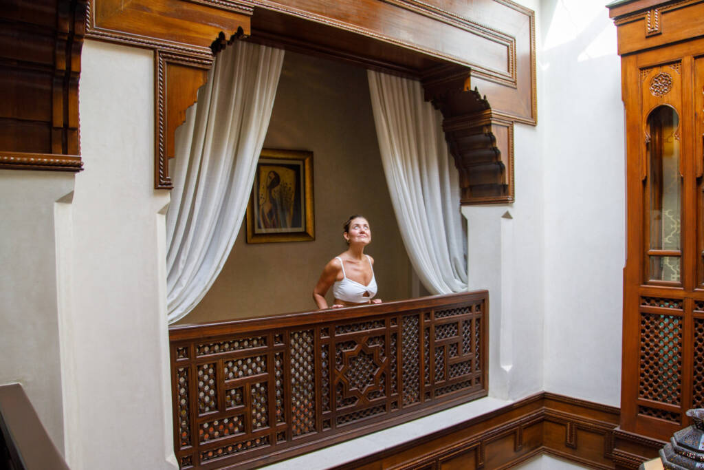 Elegant Moroccan riad courtyard with intricate zellige tiles, carved wood details, and a serene fountain, highlighting the best Morocco trip packages from the US with guided tours, luxury stays, and authentic cultural experiences.
